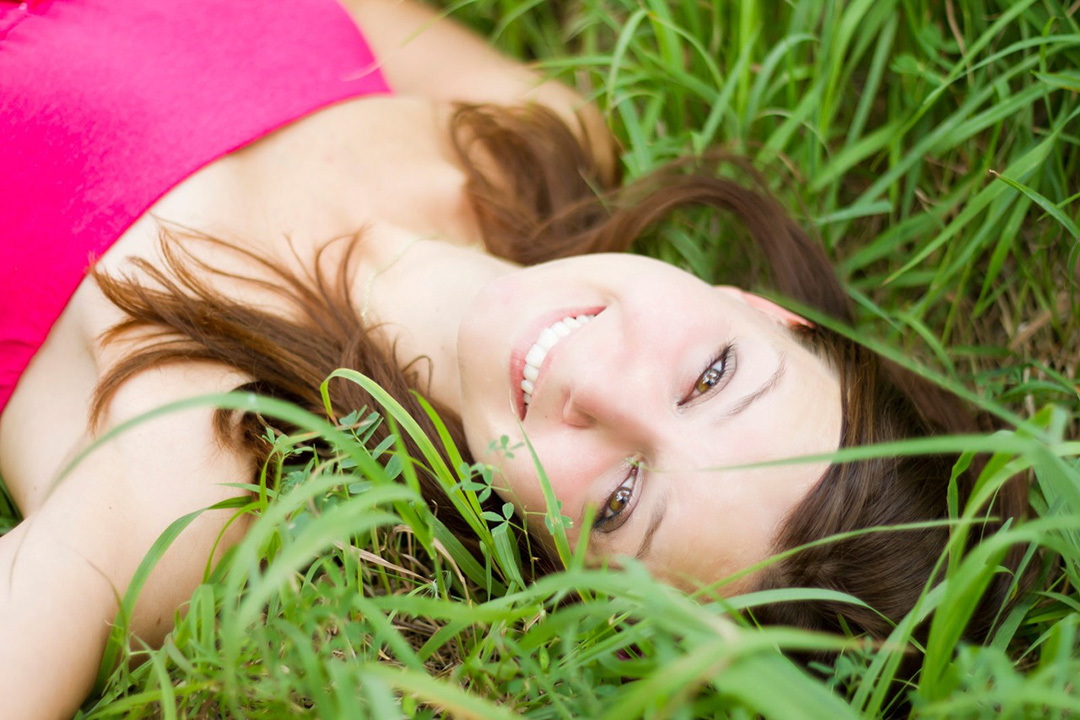 Happy woman good skin lying in grass